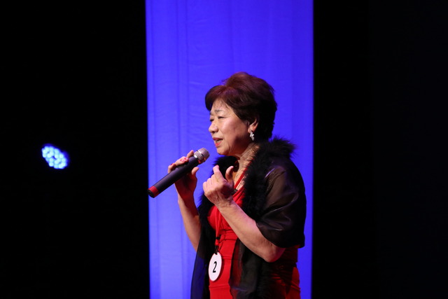 双葉ふれあい文化館にて参加ナンバー2番の女性の方が舞台で歌っている写真